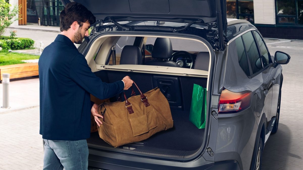 Hombre guardando su equipaje en la amplia cajuela de SUV Nissan X-Trail 2025