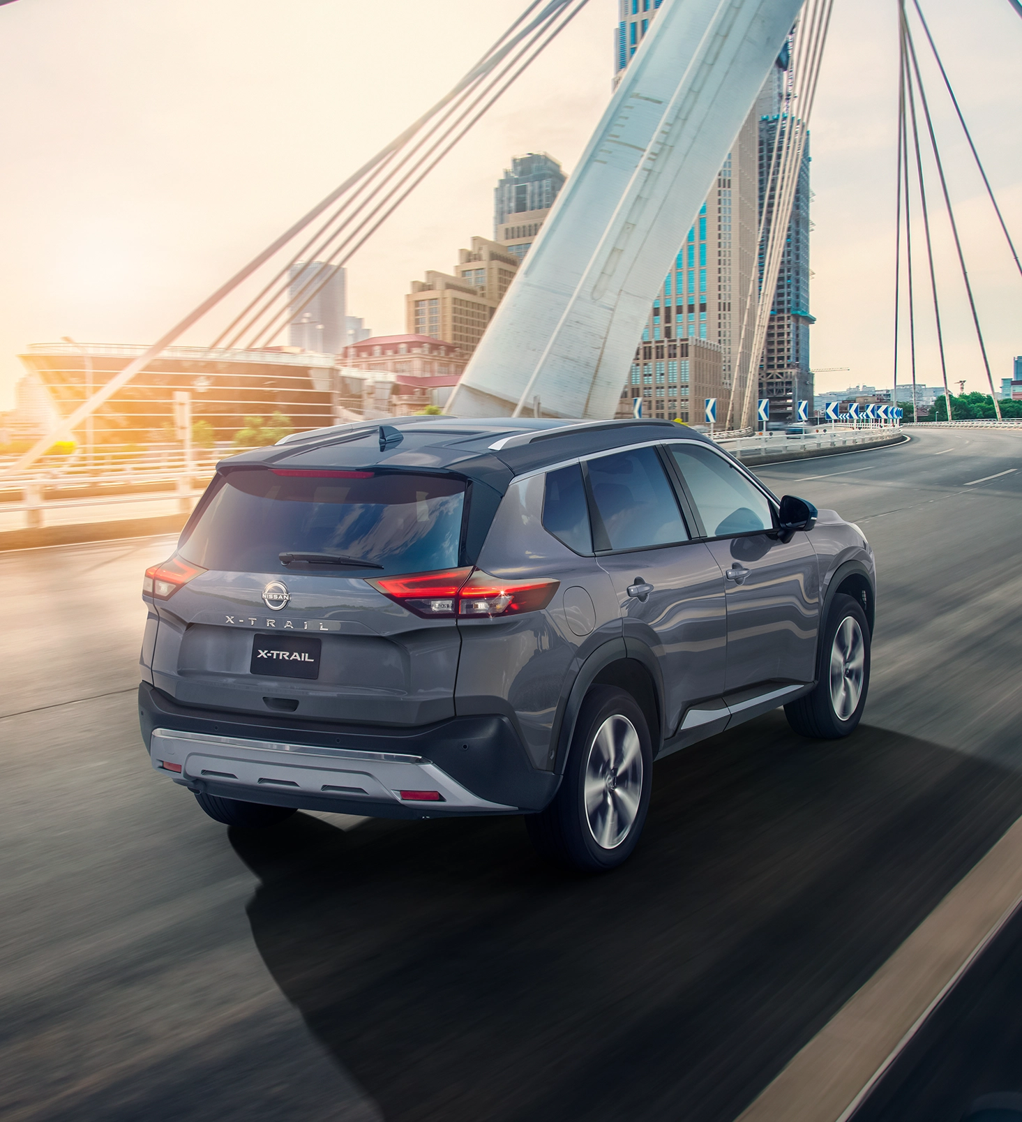 SUV de Nissan, X-Trail 2025 color gris en carrertera al atardecer