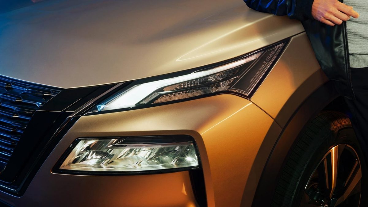 SUV Nissan X-Trail e-POWER 2025 con faros color champagne con hombre al costado con Signature Lamps con todo el poder electrizante.